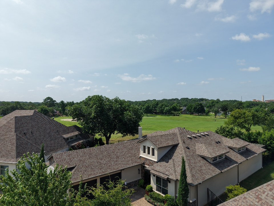 Aerial drone view of completed shingle roofs on homes overlooking a golf course in the DFW metroplex